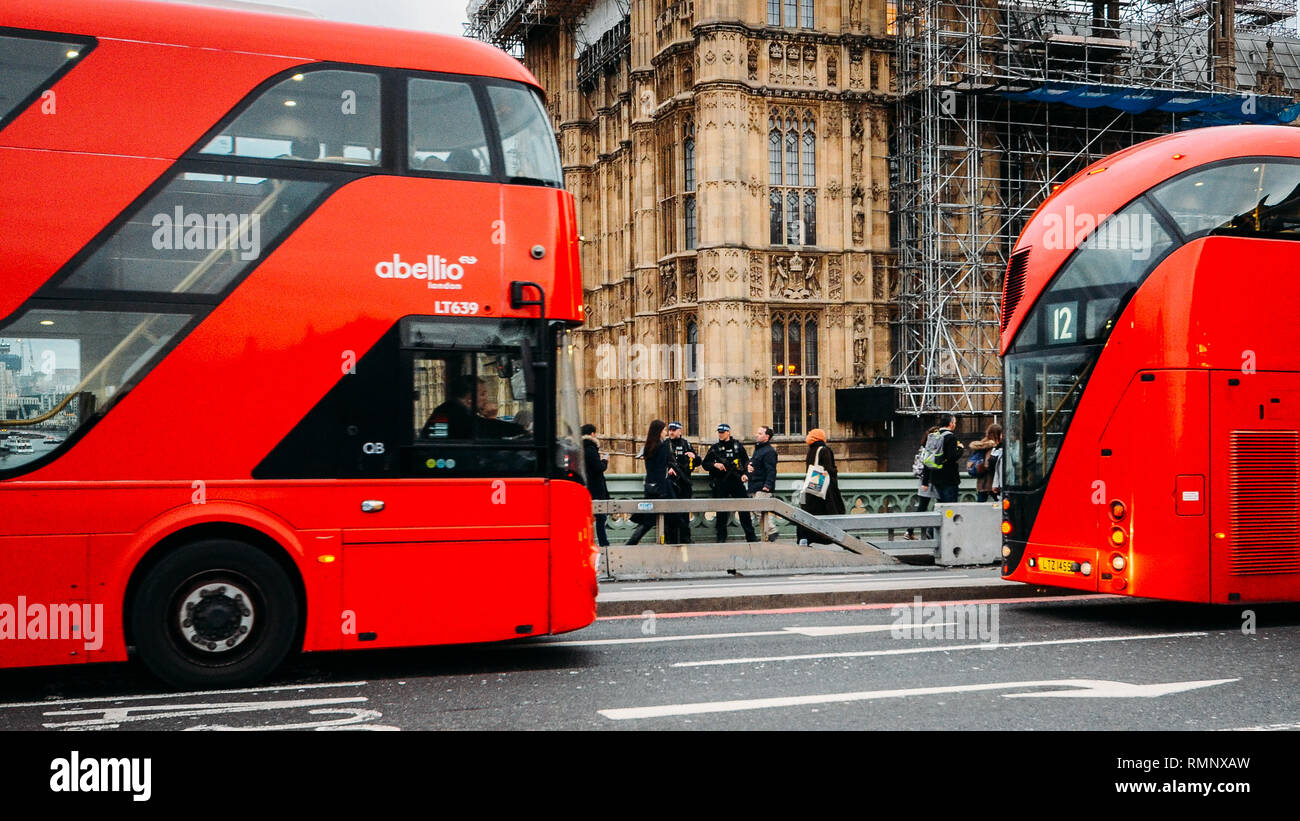 London - Feb 12, 2019: Bewaffnet bis an die Zähne zwei Polizisten sorgen für Sicherheit auf die Westminster Bridge, London von zwei roten Busse Decker gerahmt Stockfoto