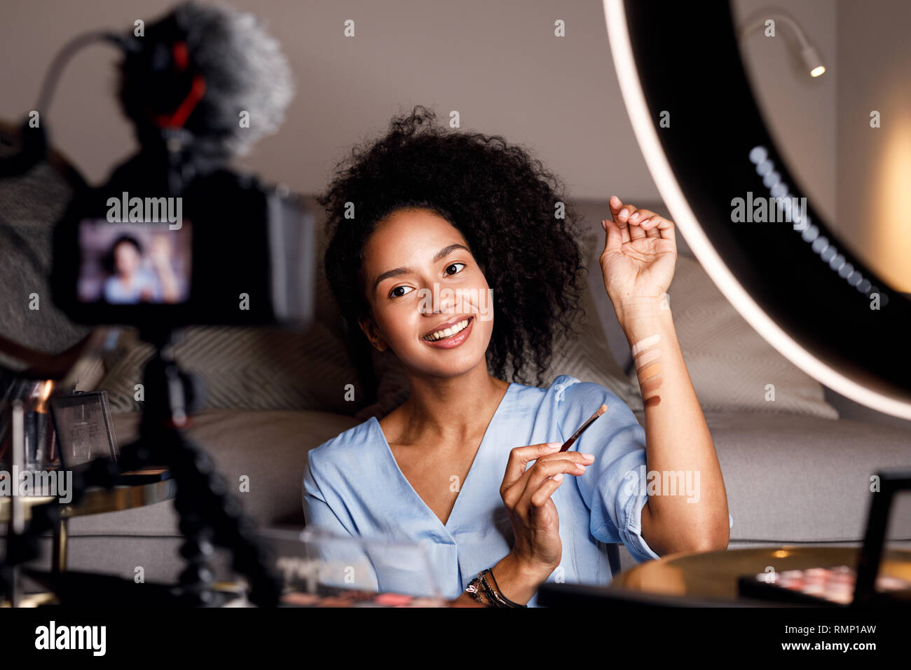 Junge Frau Aufnehmen von Videos für Ihren Online Kurs. Make-up-Artist mit Palette von tonalen Cremes auf der Hand. Stockfoto