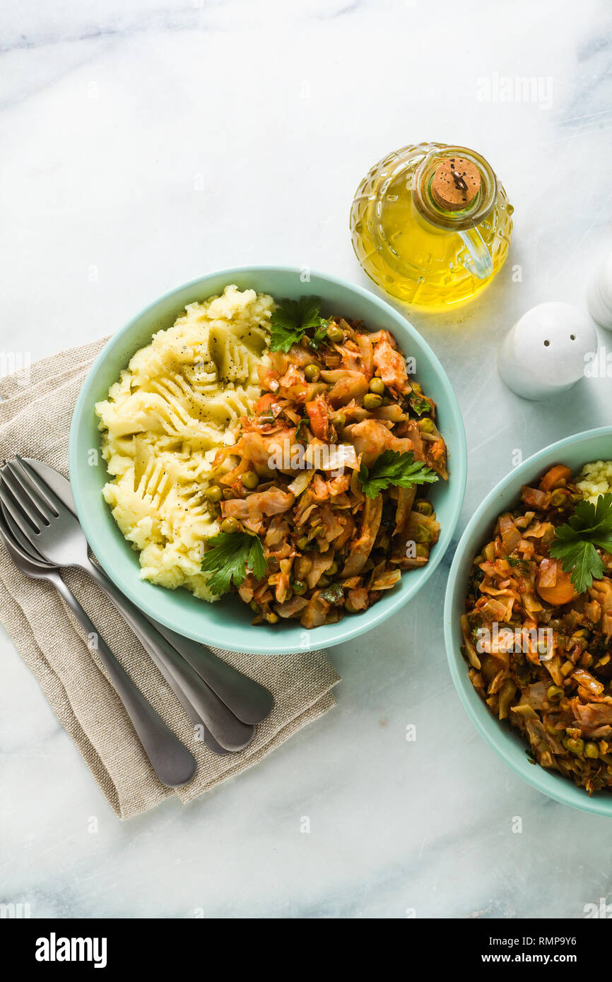 Kartoffelpüree mit Kohl Gemüseeintopf auf einem Marmortisch. Gesunde vegane Küche Stockfoto