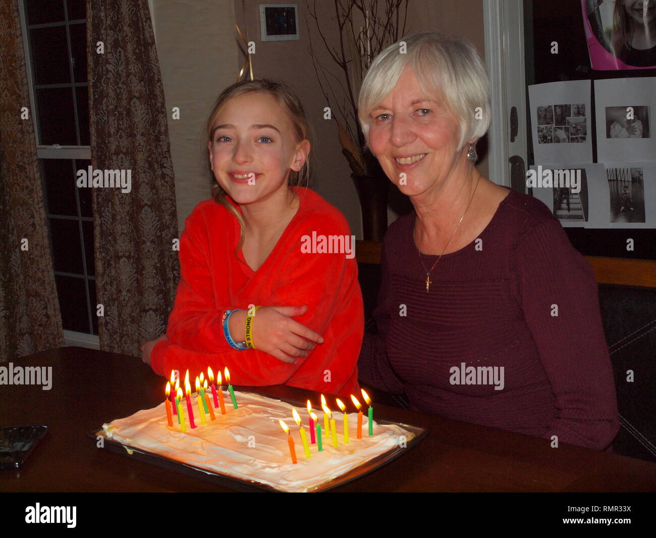 Grand Tochter Nana co-feiern am gleichen Tag Geburtstag. 60 Jahre auseinander geboren, sie feiern mit einer Geburtstagstorte und Kerzen. Stockfoto