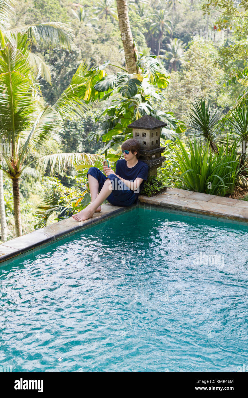 Teenager am Schwimmbad mit Handy Stockfoto