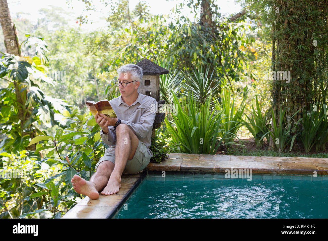Mann lesen Buch am Pool Stockfoto
