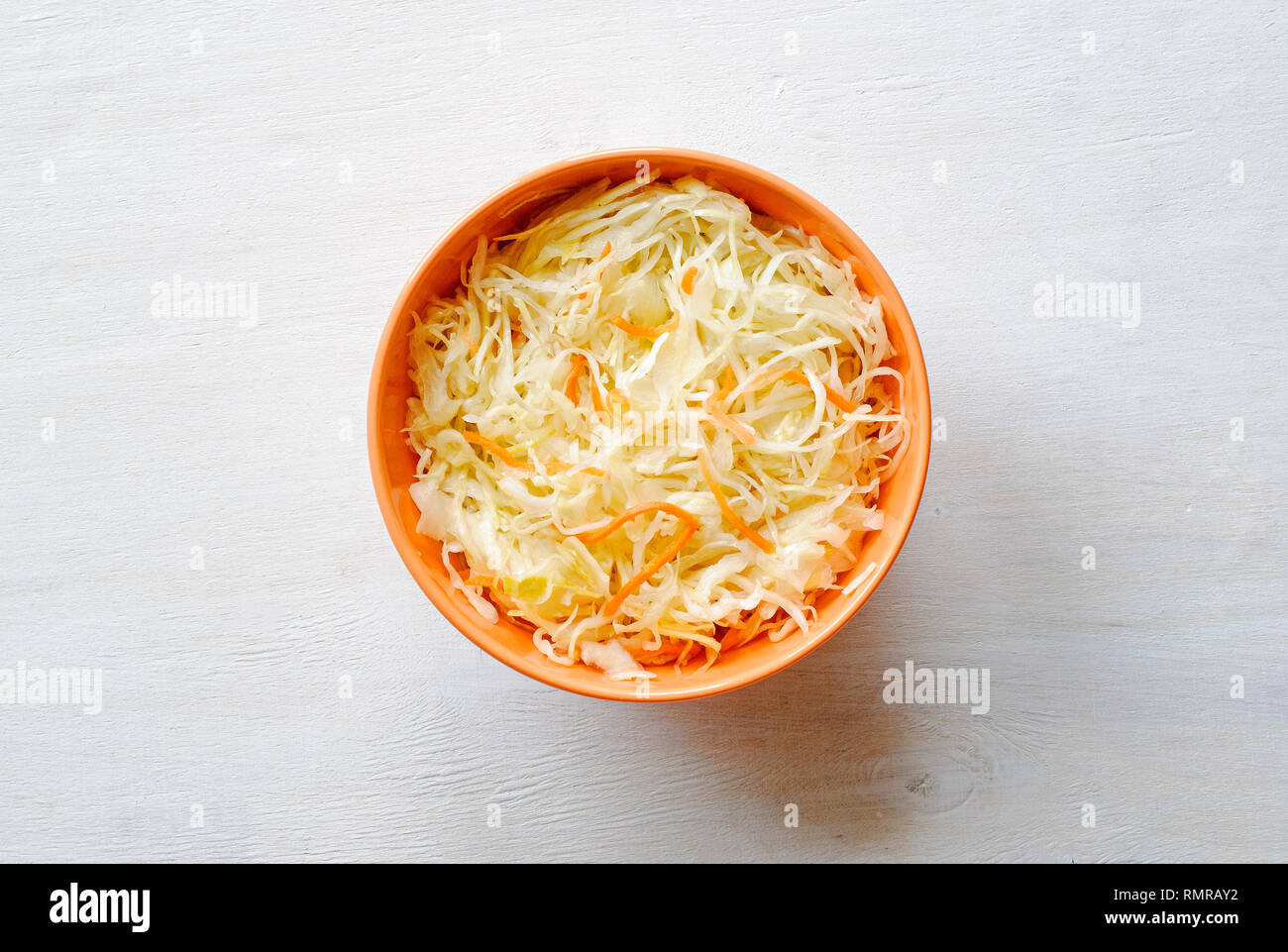 Orange Schale Zerkleinert Gemüse mit rohen gehackten Kohl und Möhren, gesehen von oben auf weißem Hintergrund Oberfläche Stockfoto