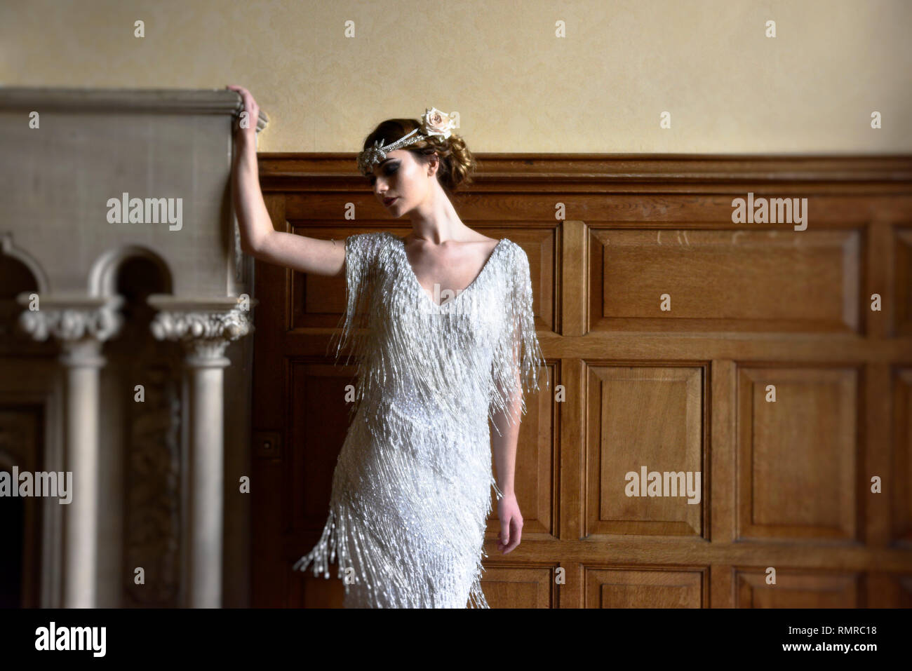 Eine schöne kaukasische Frau in einer durchgehenden langes Kleid posiert für die Kamera in ein englisches Landhaus Lage - es fühlt sich an wie eine große Gatsby ära Stockfoto