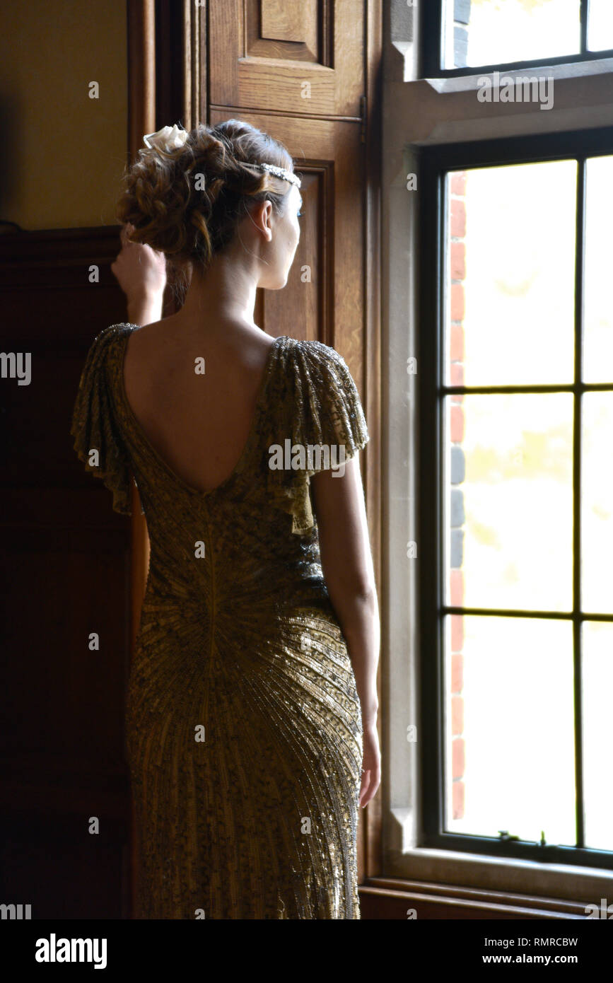 Eine schöne kaukasische Frau in einer durchgehenden langes Kleid posiert für die Kamera in ein englisches Landhaus Lage - es fühlt sich an wie eine große Gatsby ära Stockfoto