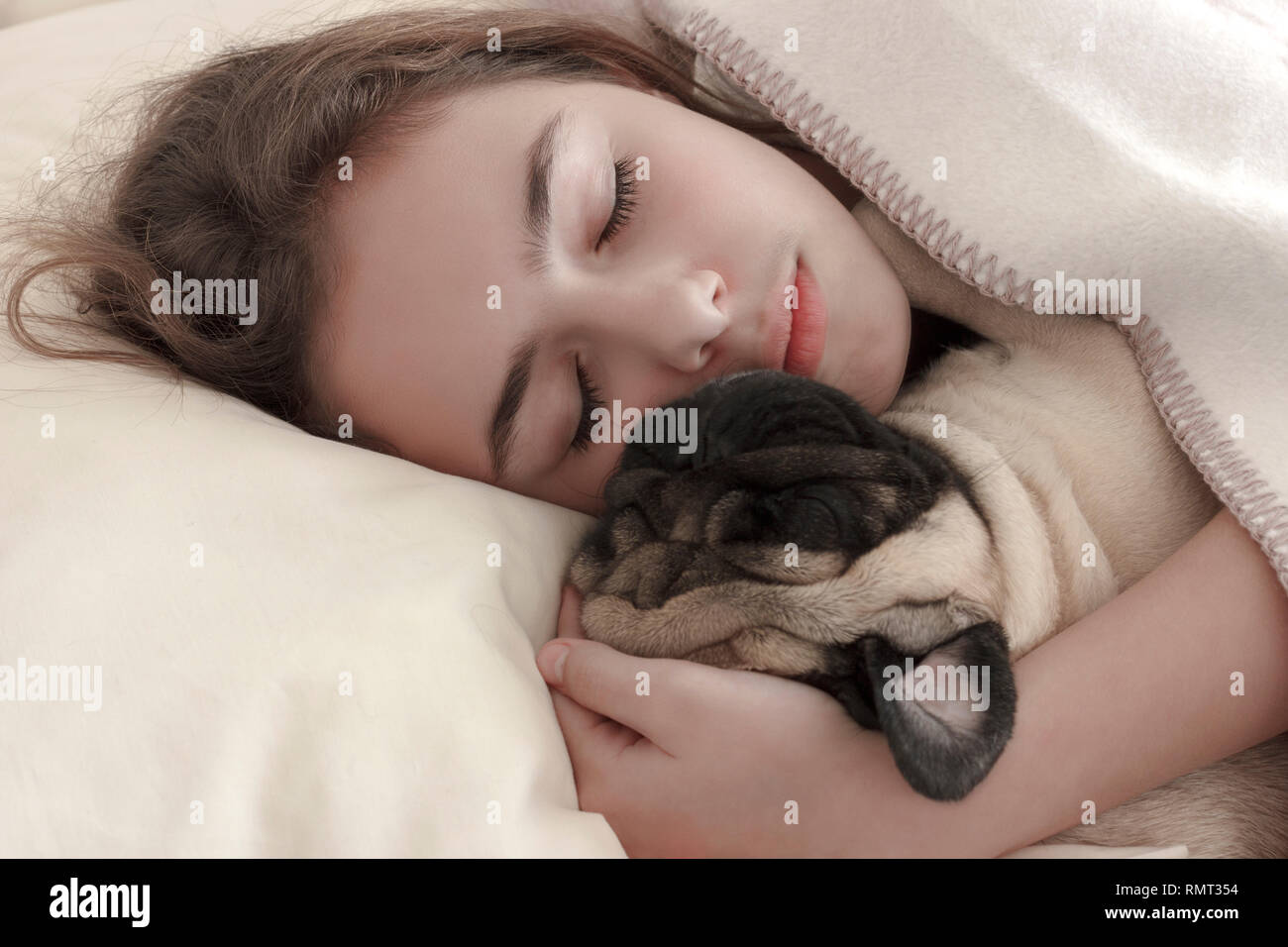Recht jugendlich Mädchen schlafen Umarmen einen Mops Hund im Bett Stockfoto