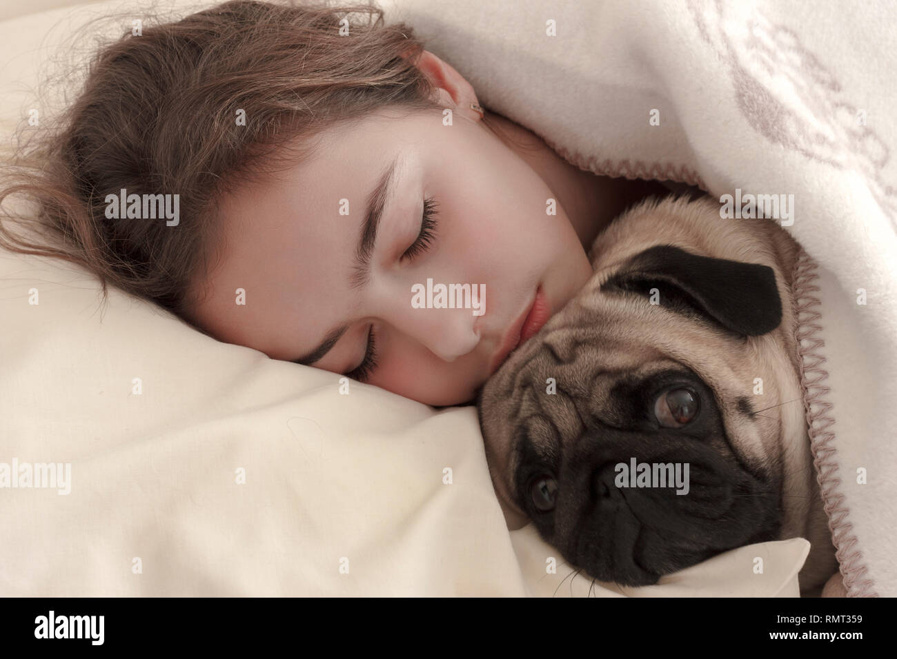 Recht jugendlich Mädchen schlafen Umarmen einen Mops Hund im Bett Stockfoto