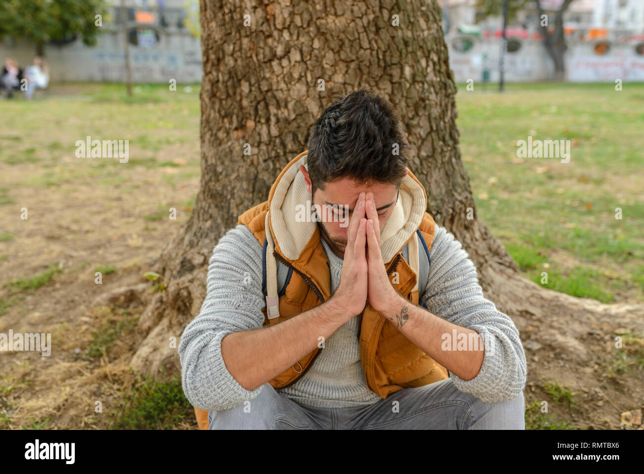 Missfallen Knabe ist das Beten zu dem Gott in der City Park Stockfoto