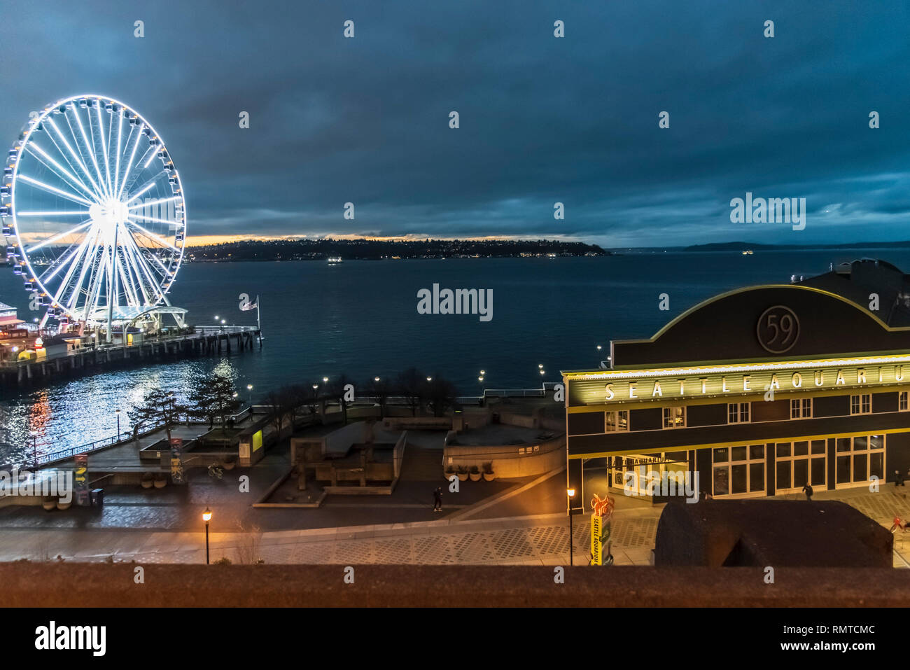 Die Seattle Downtown waterfront in der Dämmerung mit dem Riesenrad und Shops auf den Piers. Stockfoto