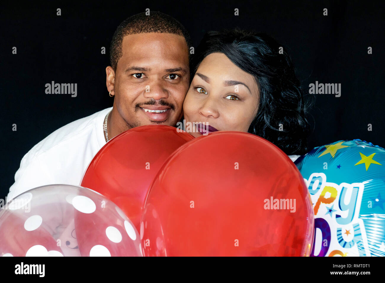 Paar in Blue Jeans mit roten Luftballons ihren Geburtstag feiern gemeinsam spielerisch Stockfoto