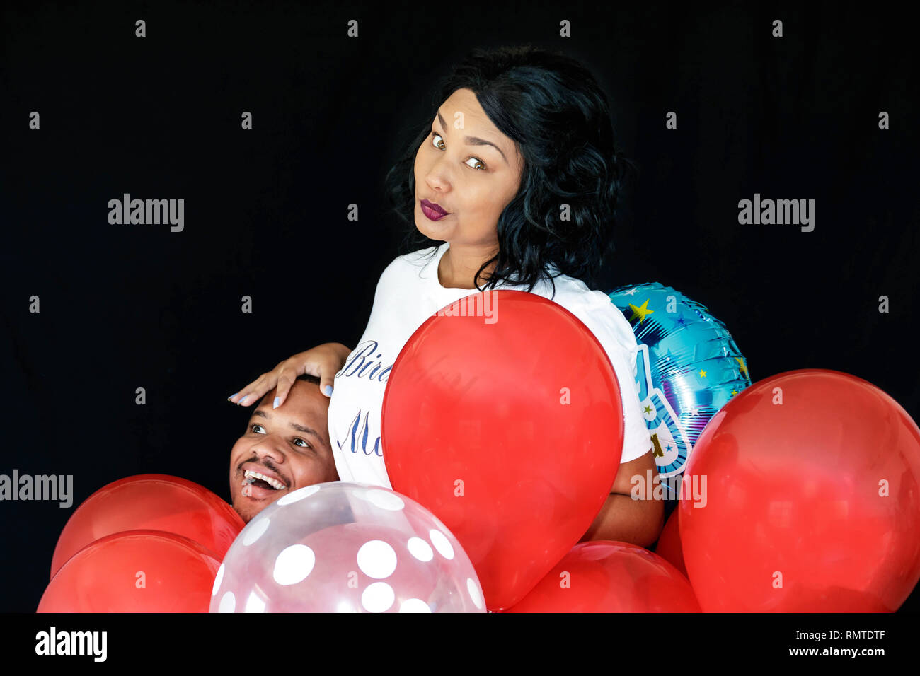 Paar in Blue Jeans mit roten Luftballons ihren Geburtstag feiern gemeinsam spielerisch Stockfoto