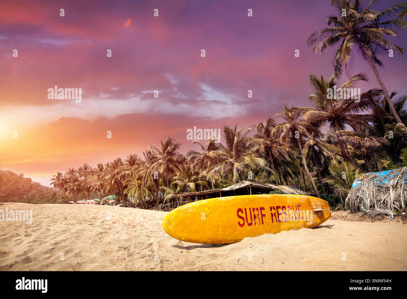 Gelbe Surf Board im Paradise tropischen Strand mit lila bewölkter Sonnenuntergang in Goa, Indien Stockfoto