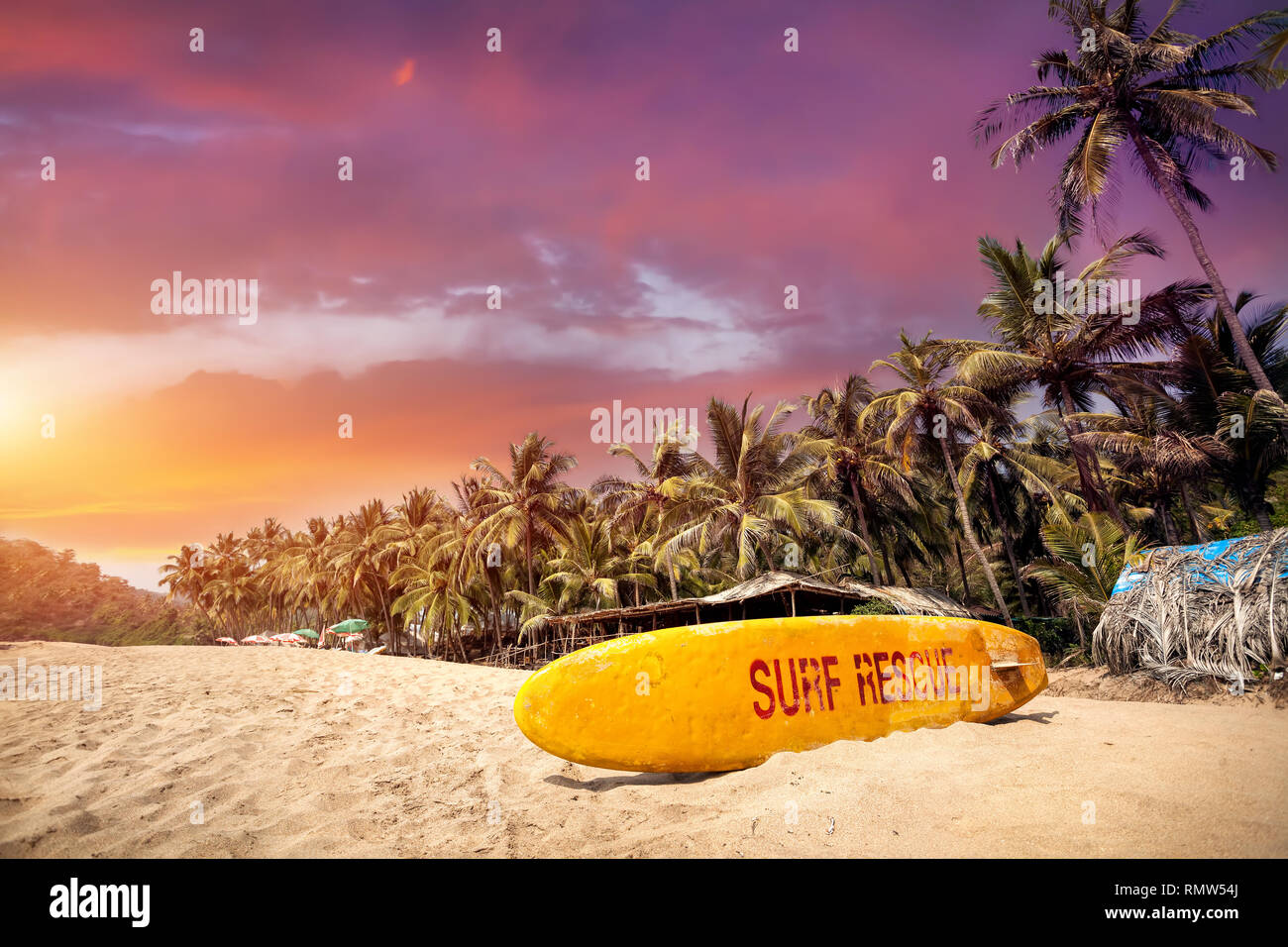 Gelbe Surf Board im Paradise tropischen Strand mit lila bewölkter Sonnenuntergang in Goa, Indien Stockfoto