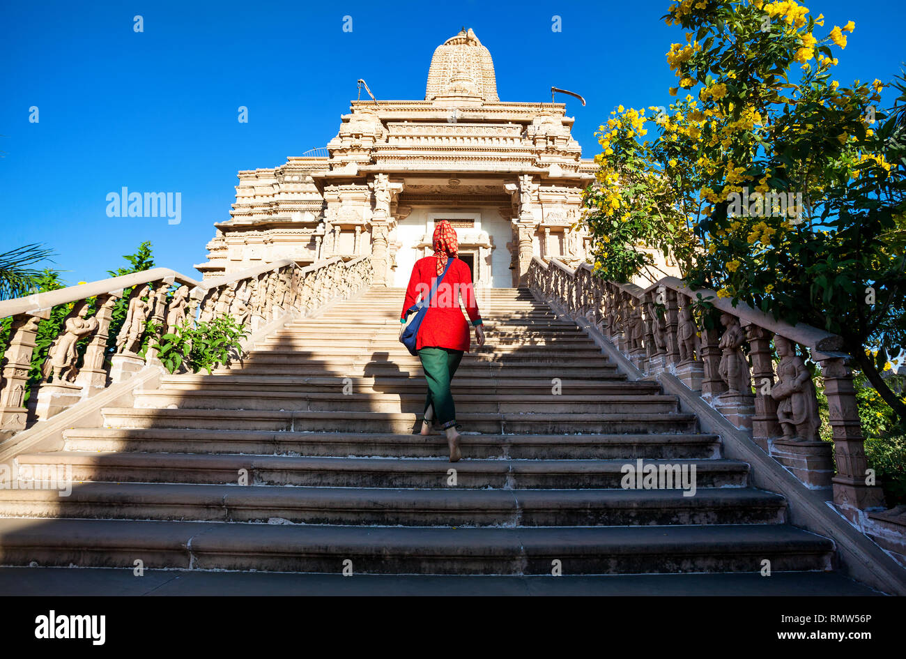 Indische Frau im roten Kleid auf der Treppe der Jain Tempel in Nasik, Maharashtra, Indien Stockfoto