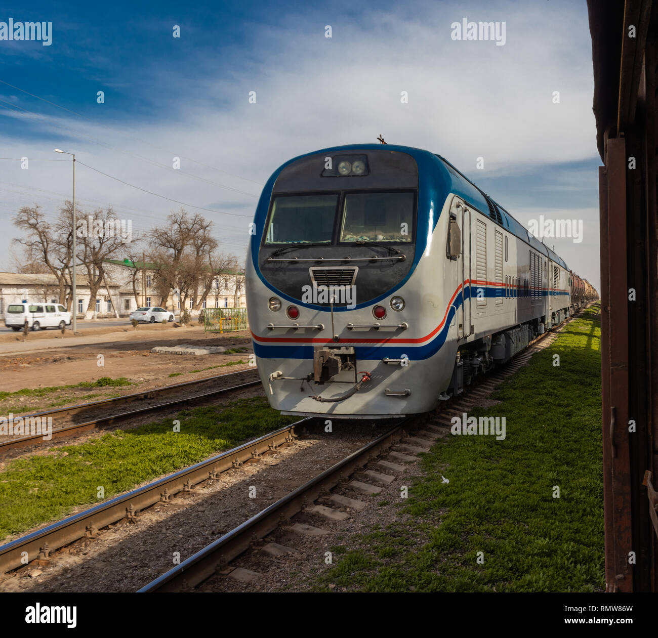 Moderne Zug auf Schienen auf dem Weg zu einem Zielpunkt auf dem Hintergrund der Blauen bewölkten Himmel. Stockfoto