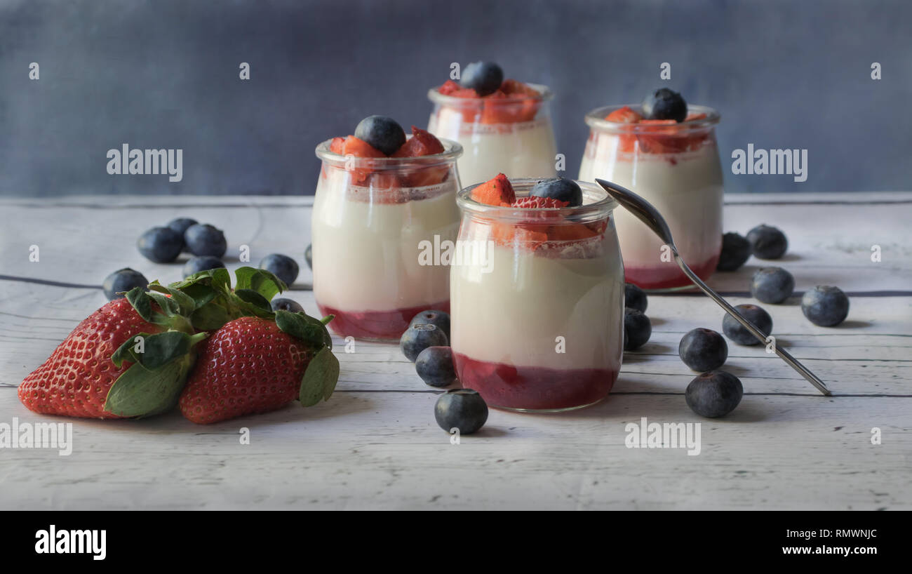 Hausgemachte Joghurt mit Erdbeermarmelade unter und Stücke von Beeren, auf ein weißes Holzbrett Stockfoto