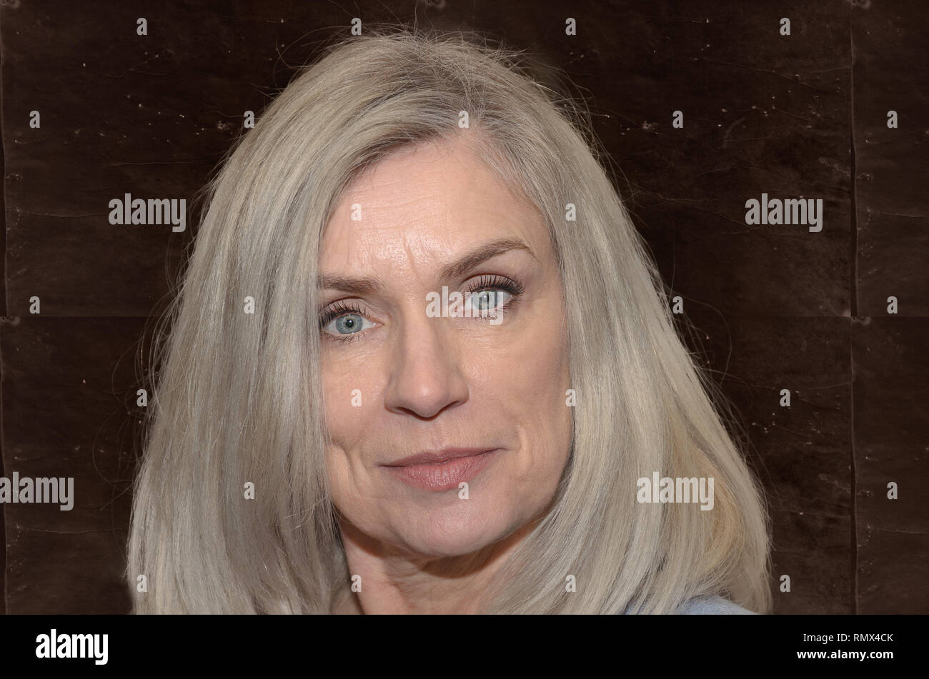 Attraktive Frau mittleren Alters mit langen blonden Haaren und blauen Augen in die Kamera mit einem ruhigen Lächeln in einer Nahaufnahme Kopf geschossen Stockfoto