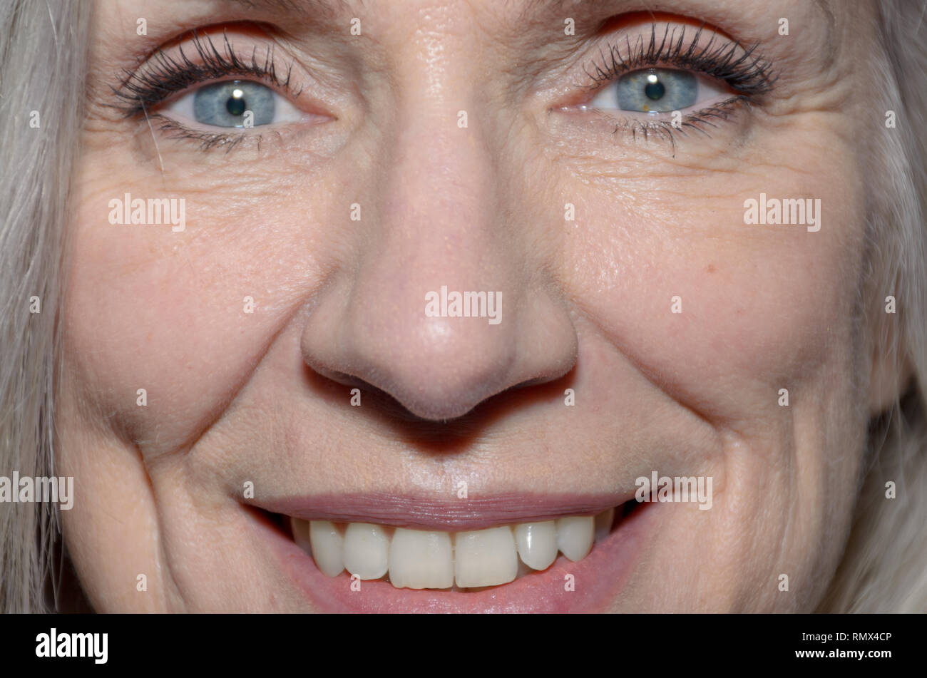 Frau mittleren Alters mit einem glücklichen Lächeln blaue Augen und Mund in Nahaufnahme 7/8-Sicht auf Ihre Funktionen Stockfoto