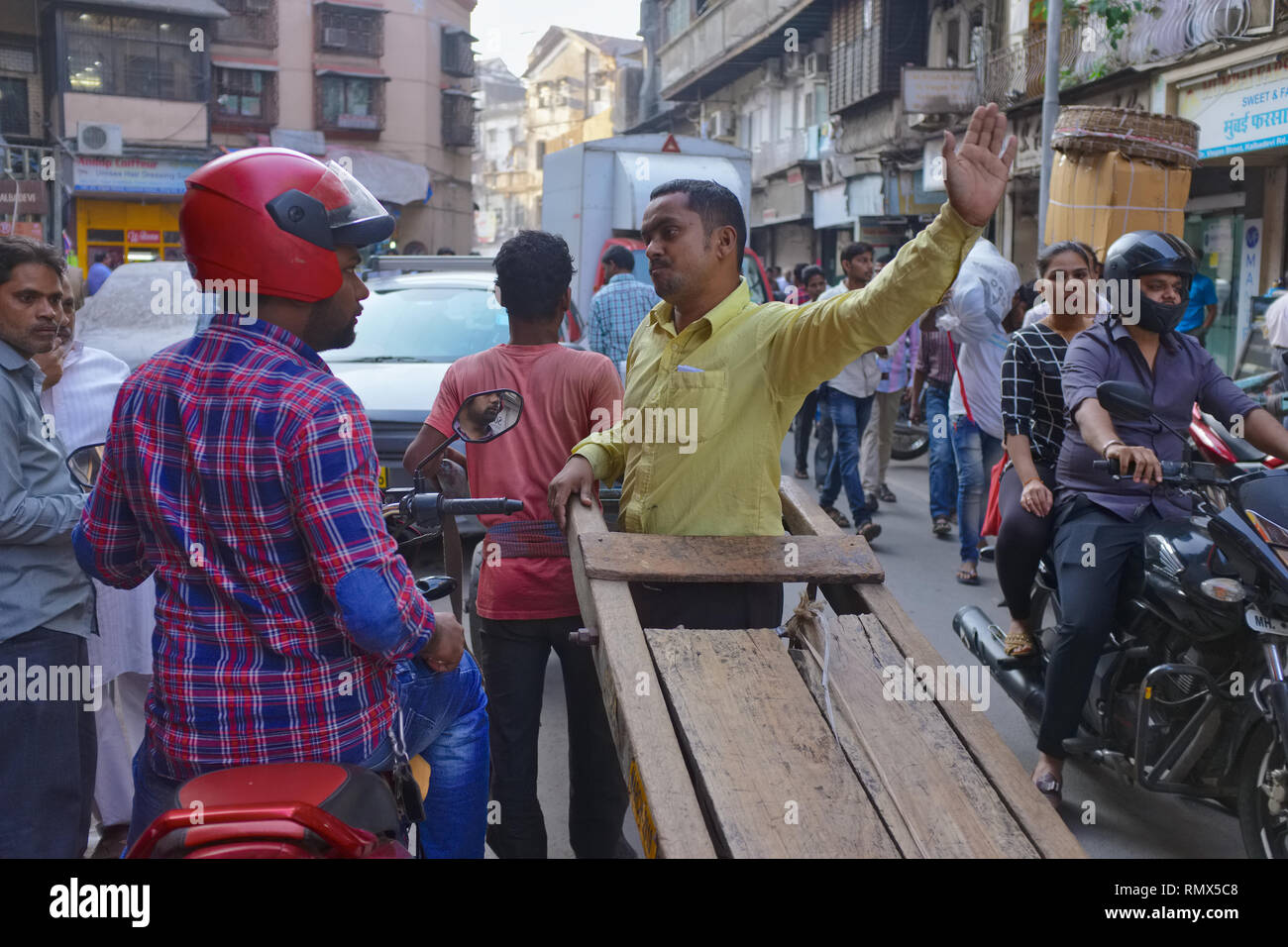 Ein Streit bricht aus zwischen einem Handwagen Abzieher und ein Motorrad fahrer in einem engen von - Spur der Kalbadevi Road Handel in Bhuleshwar, Mumbai, Indien Stockfoto