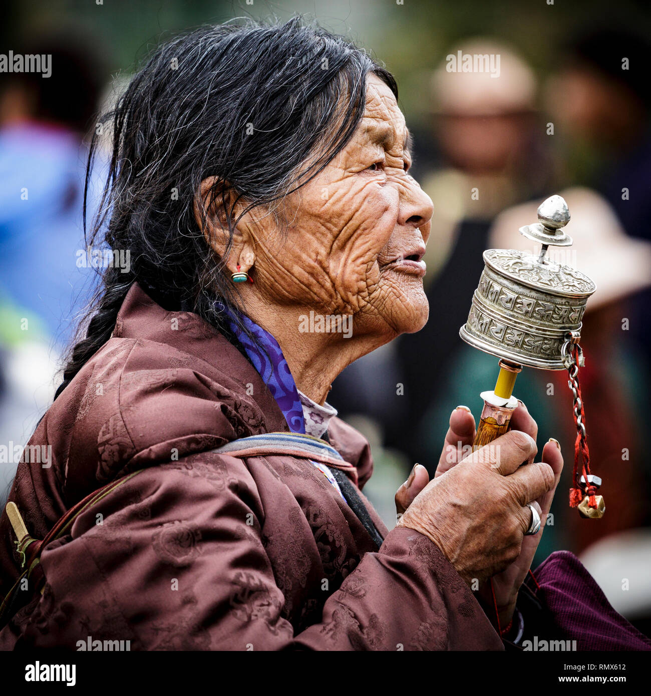 Lhasa, Tibet. Juli 2016 20. Nahaufnahme Porträt einer ethnischen Frau in traditioneller Kleidung beten mit dem Handheld Gebetsmühle. Foto: Bryan Wa Stockfoto