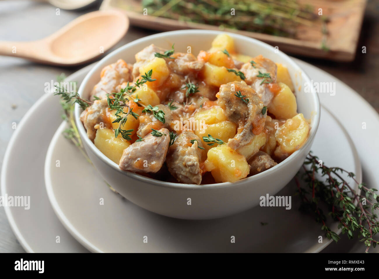 Irish Stew bestreut mit Grün Thymian. Fleisch geschmort mit Kartoffeln, Karotten und Gewürzen auf Holz- Hintergrund. Stockfoto