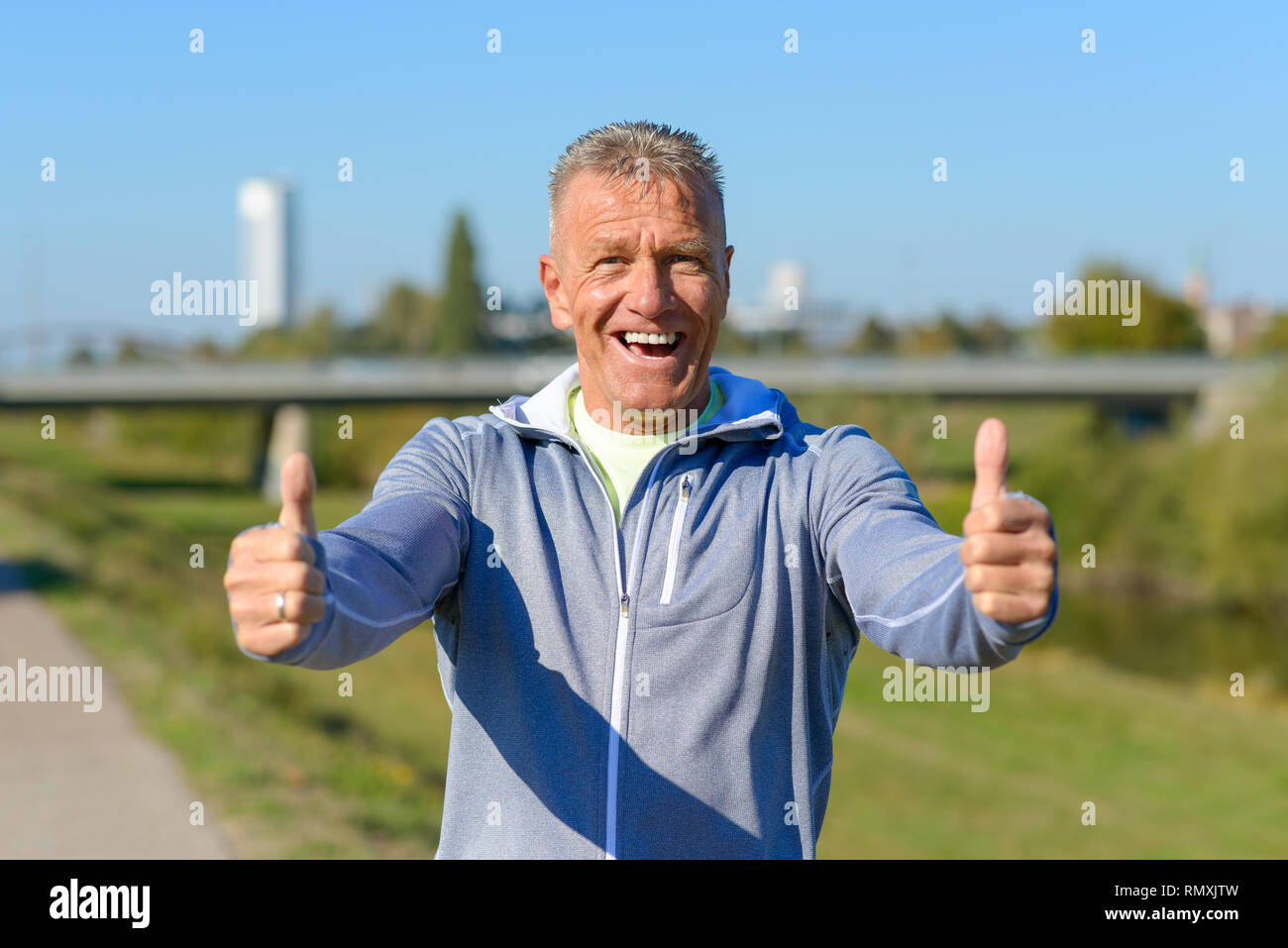 Enthusiastisch motivierten attraktiv im mittleren Alter Mann, der einen Daumen nach oben Geste der Anerkennung und Erfolg mit einem strahlenden Lächeln Stockfoto