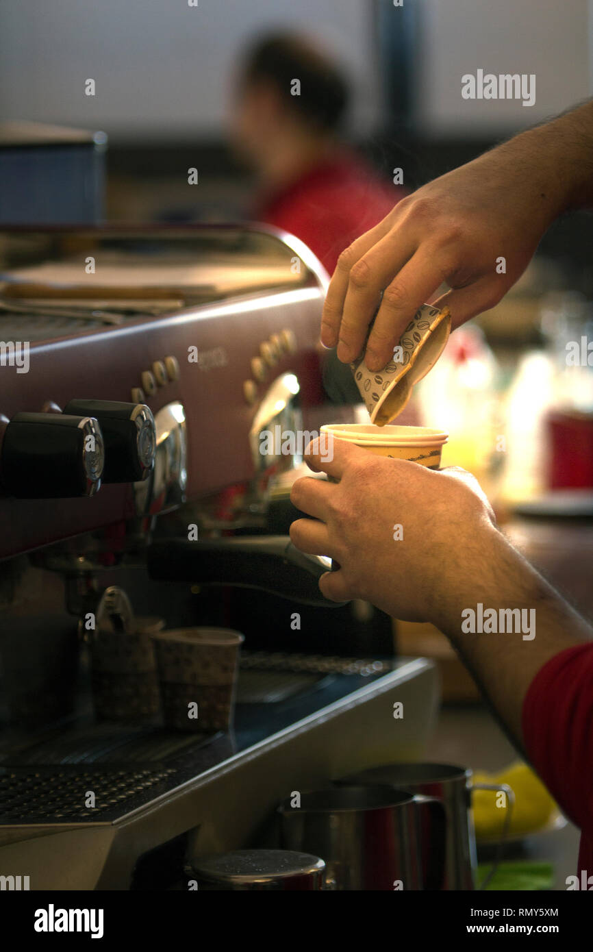 Die Hände eines männlichen Barista quetschen eine Tasse Espresso in eine andere Tasse. Stockfoto