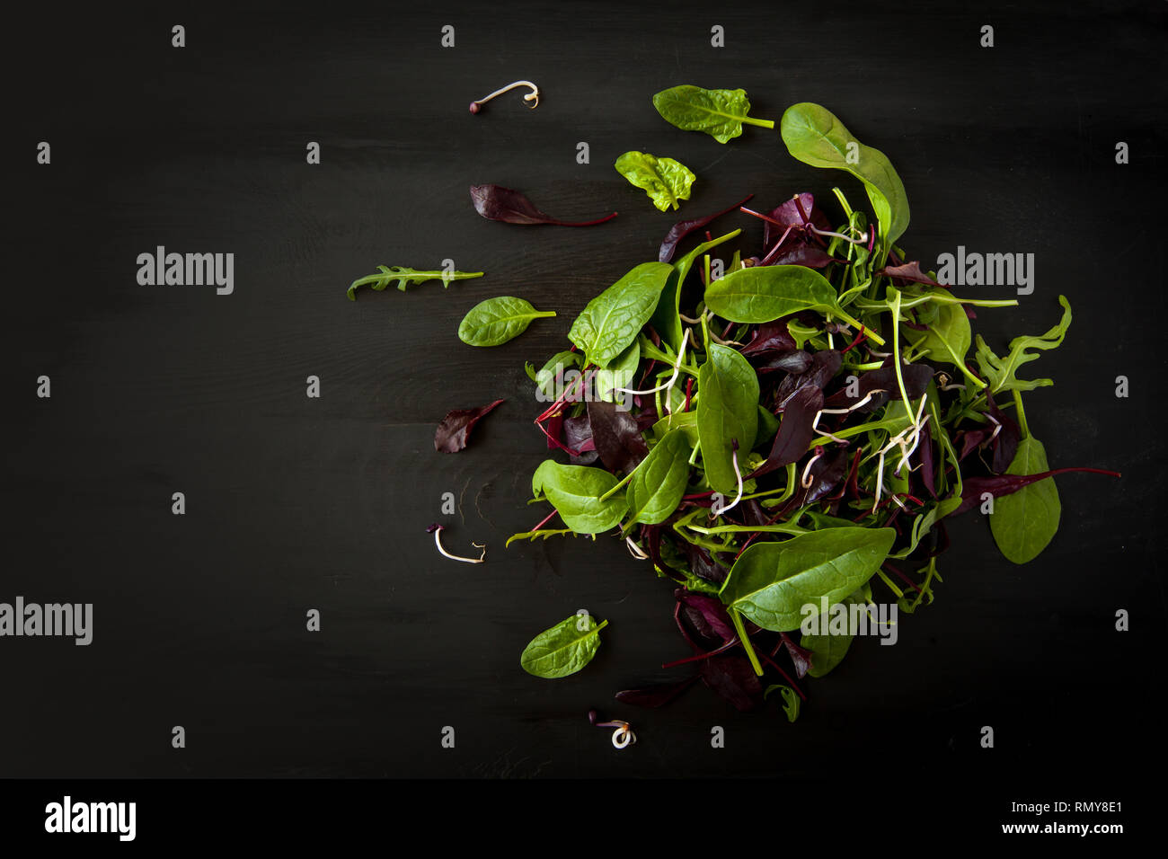 Frühling detox Salat Mix mit Rucola, Rote Beete, Spinat und Rosenkohl auf dunklen Holzplatte auf schwarzen Hintergrund, Ansicht von oben. Stockfoto