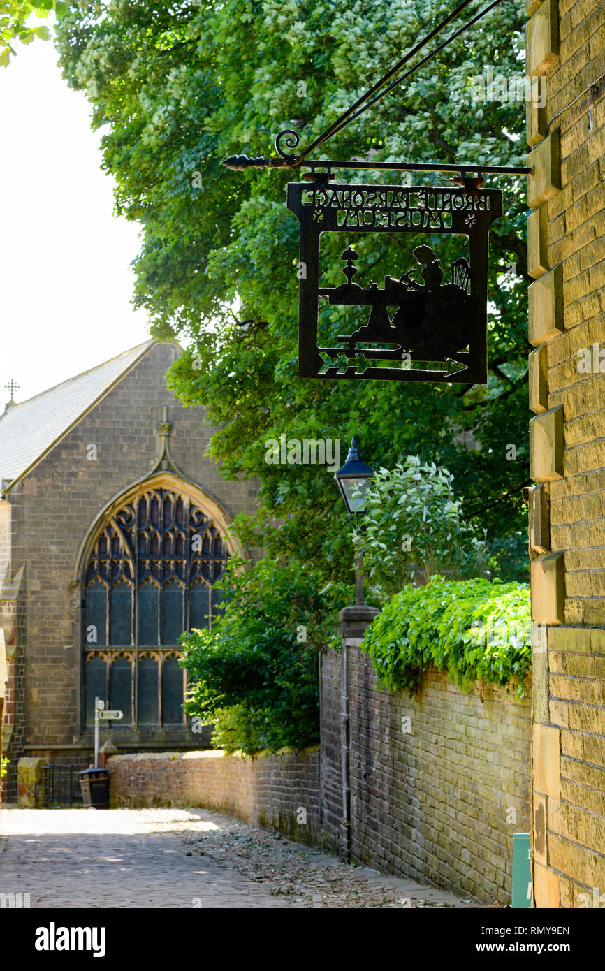 Close-up Schwarz metall Schild hängen an der Außenwand Bronte Parsonage Museum (Brontes home) & Kirche jenseits - Haworth, Yorkshire, England, UK. Stockfoto