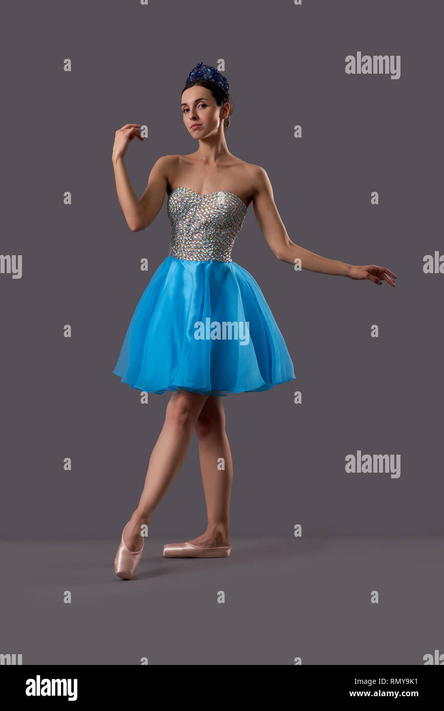 Junge Ballerina trägt blaue Kleid, Ballett Schuhe und Krone bei Kamera und  posiert im Studio. Professionelle Tänzerin auf grauen Hintergrund isoliert.  Konzept der Ballett Art Stockfotografie - Alamy