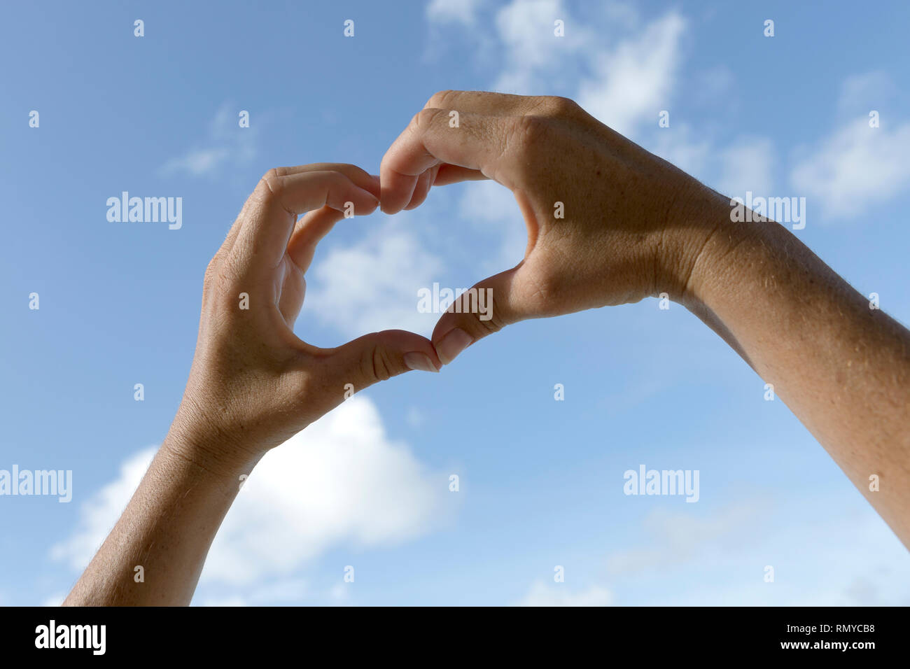 Weibliche Hände vor blauen sonnigen Himmel, Ferienhäuser Hintergrund Stockfoto