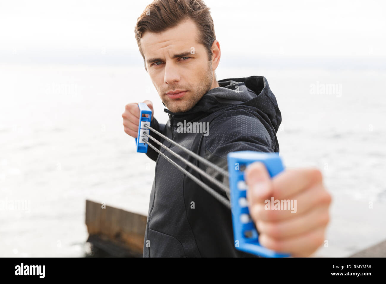 Schön selbstbewussten jungen Sportler, am Strand, mit Brust Expander Stockfoto