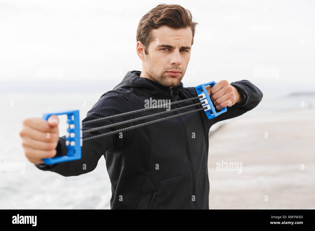 Schön selbstbewussten jungen Sportler, am Strand, mit Brust Expander Stockfoto