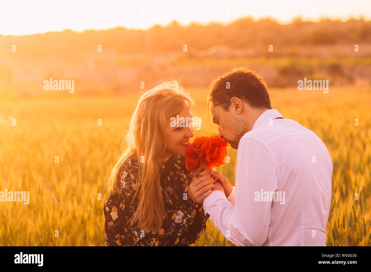 Mann und Frau riecht Bouquet von Mohnblumen im Weizenfeld auf die Dämmerung, Malta Stockfoto