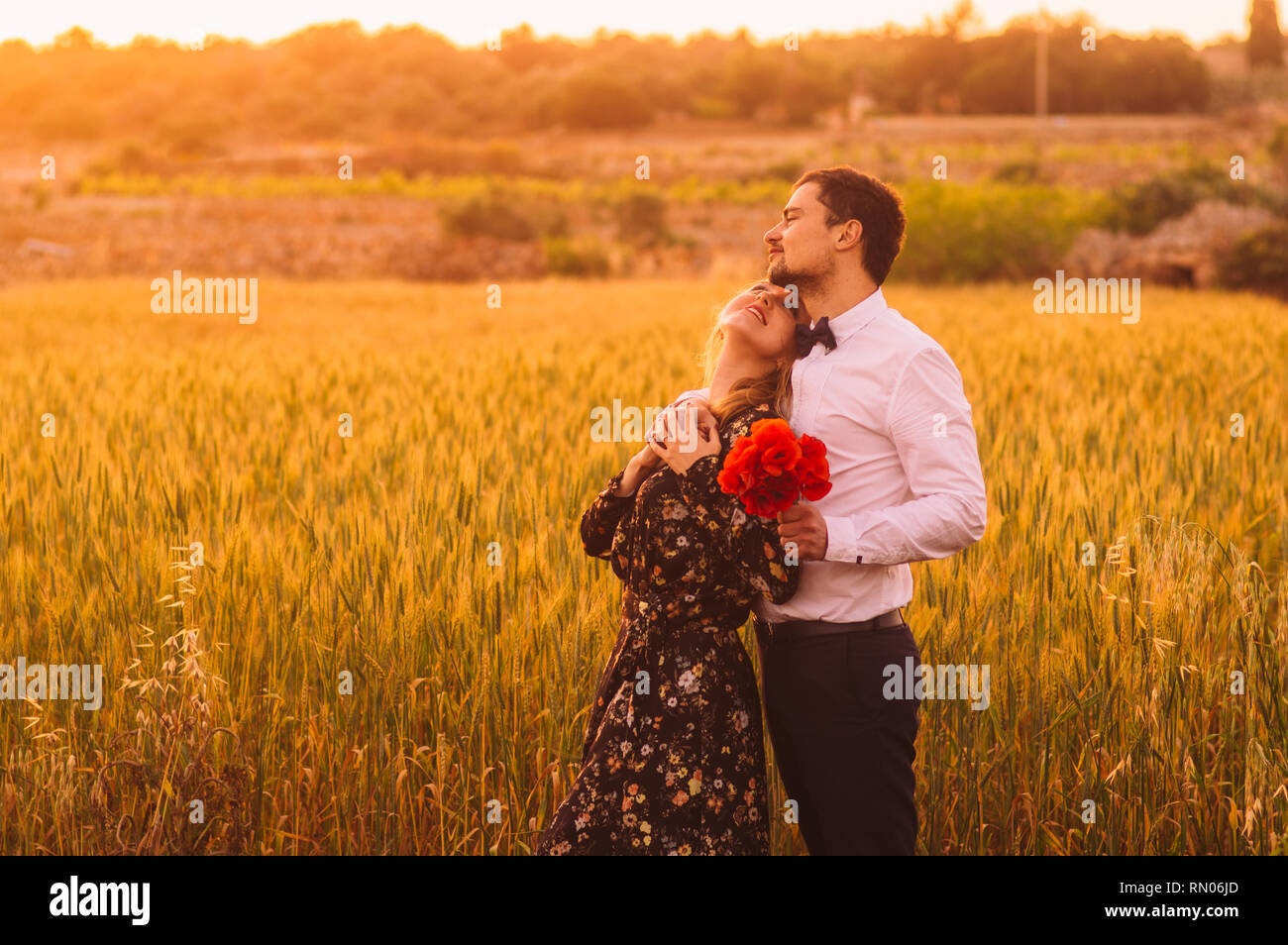 Der Mann und die Frau mit Blumenstrauß von Mohn im Weizenfeld auf die Dämmerung, Malta Stockfoto