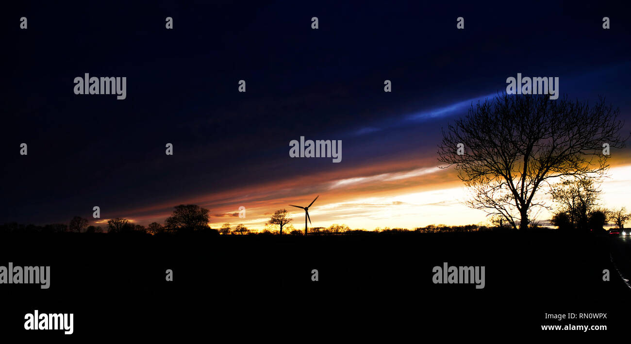 Eine einzelne Windenergieanlage in der Ferne über Felder in einem typischen englischen Country Szene bei Sonnenuntergang Stockfoto