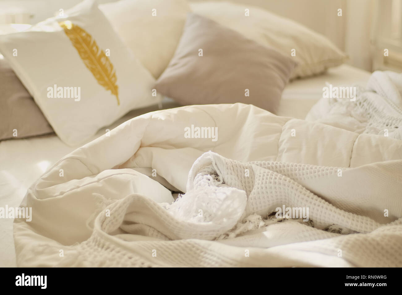 Unordentliche Bett. Weiß Kissen mit Decke auf dem Bett ungemacht. Konzept der Entspannung nach Morgen. Mit beleuchtung Fenster. Ansicht von oben. Stockfoto