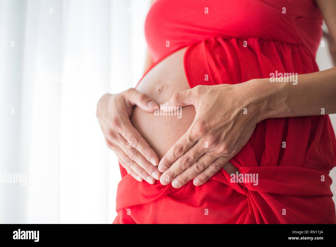 Schwangere Frau ihre Hände halten in Form eines Herzens auf dem Bauch Stockfoto