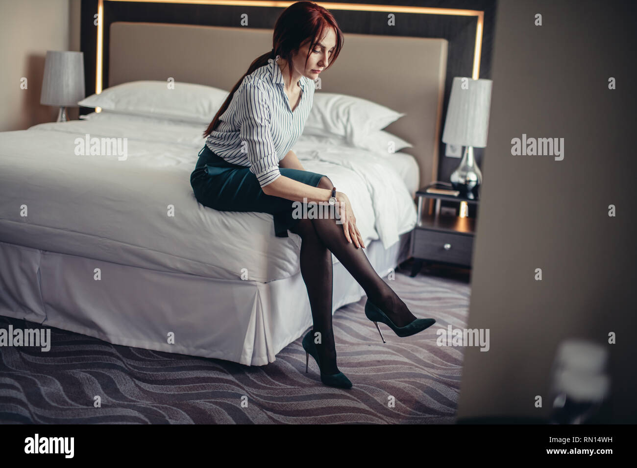 Junge weibliche Chef Assistant setzt sich auf Ihren High Heel Schuhe beim  Sitzen auf dem Bett im Schlafzimmer mit luxuriösem Interieur  Stockfotografie - Alamy