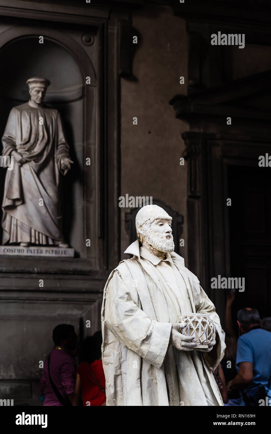 Lebende statue Mönch. Statue Cosimo di Giovanniin Piazzale in den Nischen der Uffizien Kolonnade im Hintergrund. Florenz. Italien Stockfoto