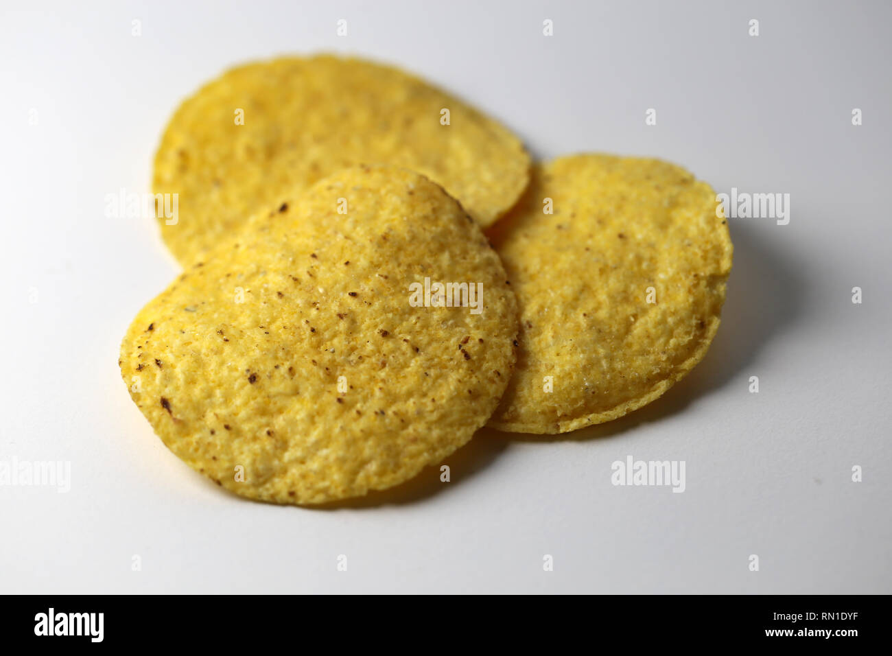 Eine Nahaufnahme von drei golden braun Nachos auf einem weißen Tisch. Lecker und knackige Snack! Auf einem weißen Tisch fotografiert. Farbe Bild mit Makro Objektiv aufgenommen Stockfoto