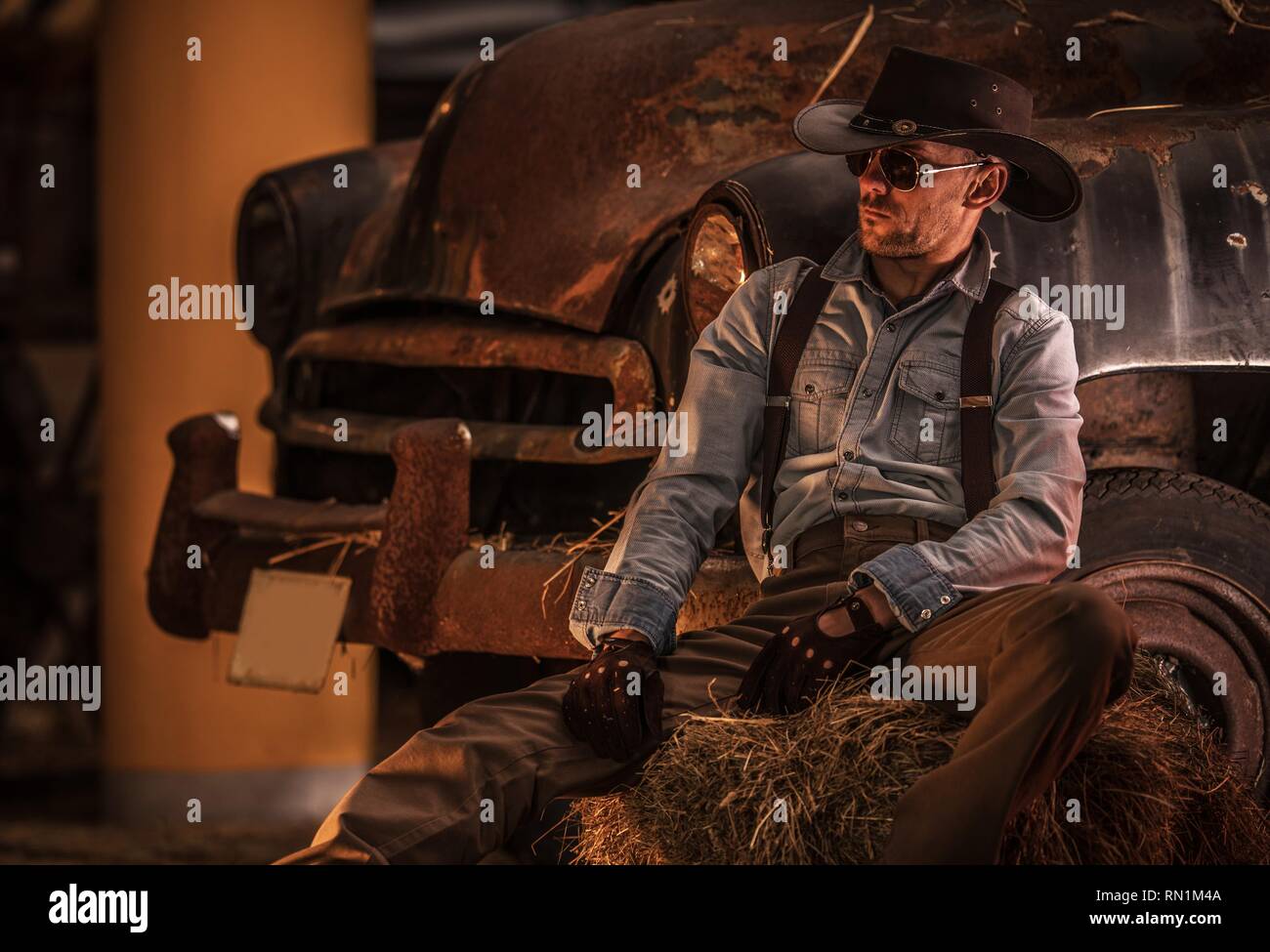 Kaukasische Cowboy in seinem 30s und rostigen Oldtimer in der Scheune. Stockfoto