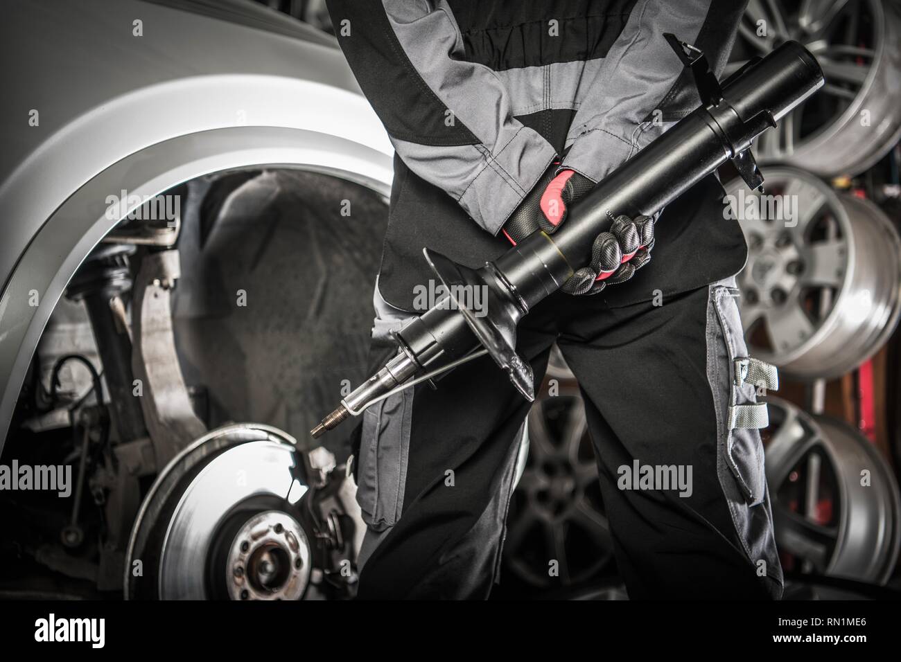Automotive Konzept. Automechaniker mit Stoßdämpfer hydraulische Gerät in die Hände der Vorbereitung für erforderliche Absorber ändern. Stockfoto