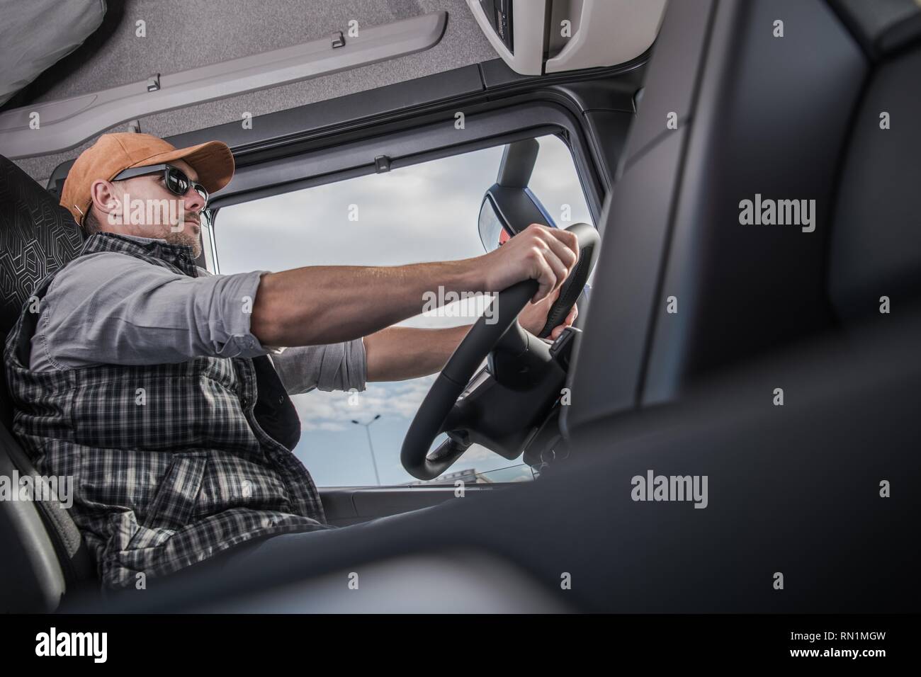 Kaukasische Fahrer tragen Sonnenbrillen im Inneren moderne Sattelschlepper LKW-Kabine. Transport- und Automobilindustrie. Kommerzielle Fahrt. Stockfoto