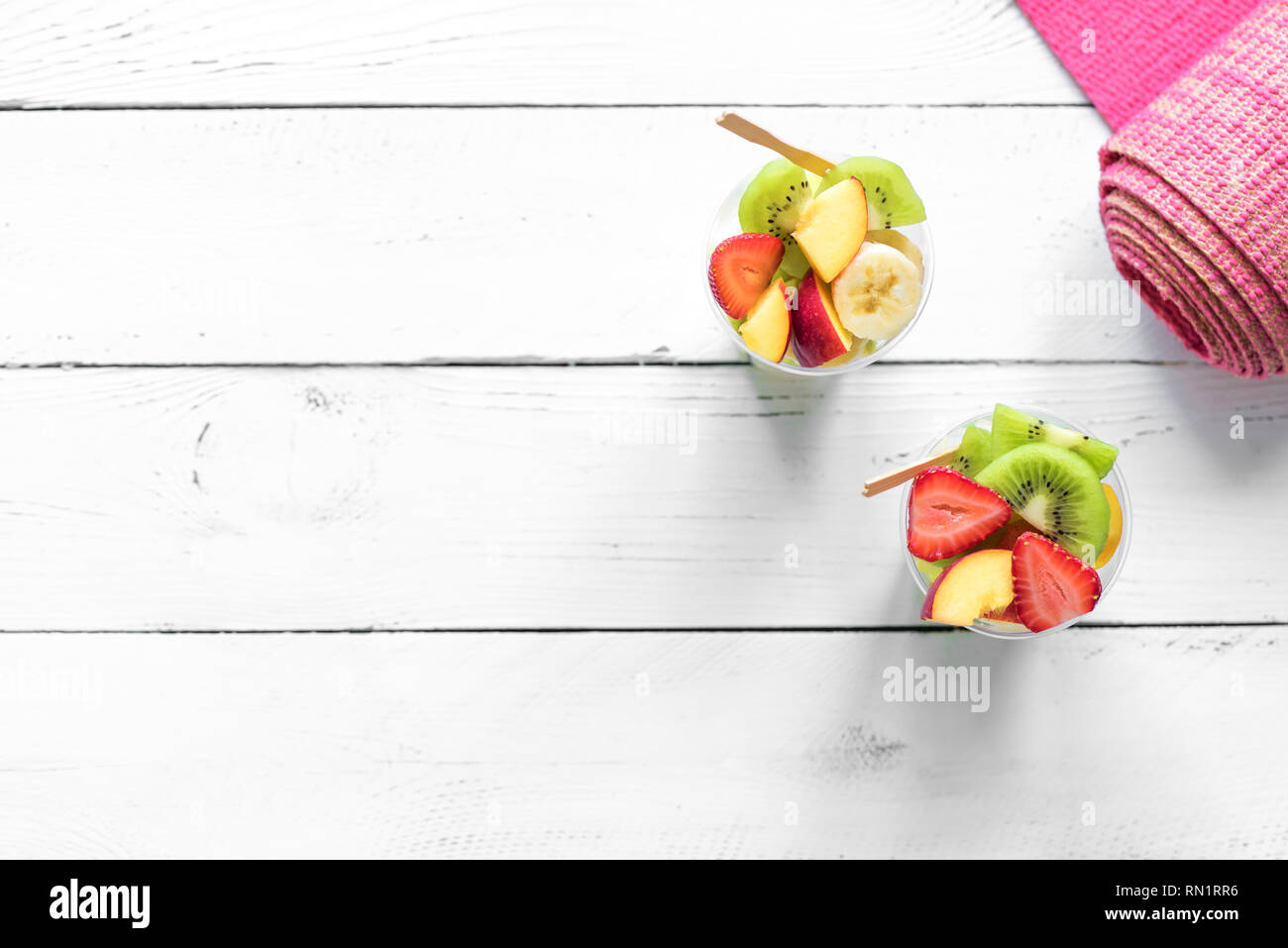 Feminine Sport und gesunder Lebensstil Konzept. Rosa Yoga Matte und Obst und Beeren Salat in Schale aus Kunststoff zu gehen, Platz kopieren, Ansicht von oben. Stockfoto