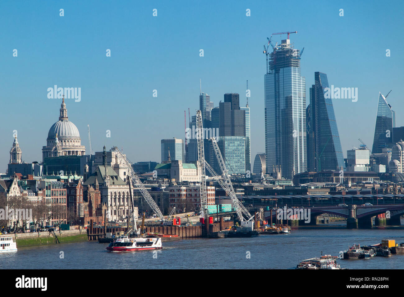 Ein heller, sonniger Tag Blick flussaufwärts an der St Paul's Cathedral und die Wolkenkratzer der Stadt London an einem sonnigen Tag Stockfoto