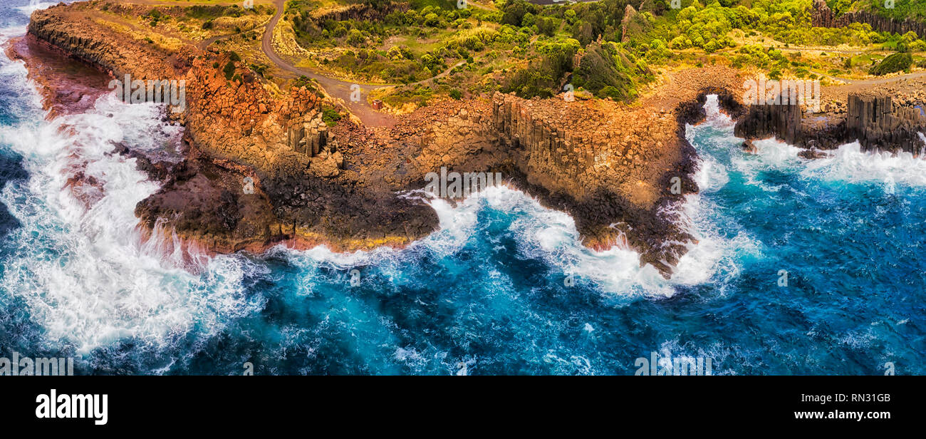 Robuste coasline von Bombo Steinbruch Landspitze auf australischen Pazifikküste mit geologischen Basalt sechseckige Pinnacle Felsen bis in Surfen wav Ständigen erodiert Stockfoto