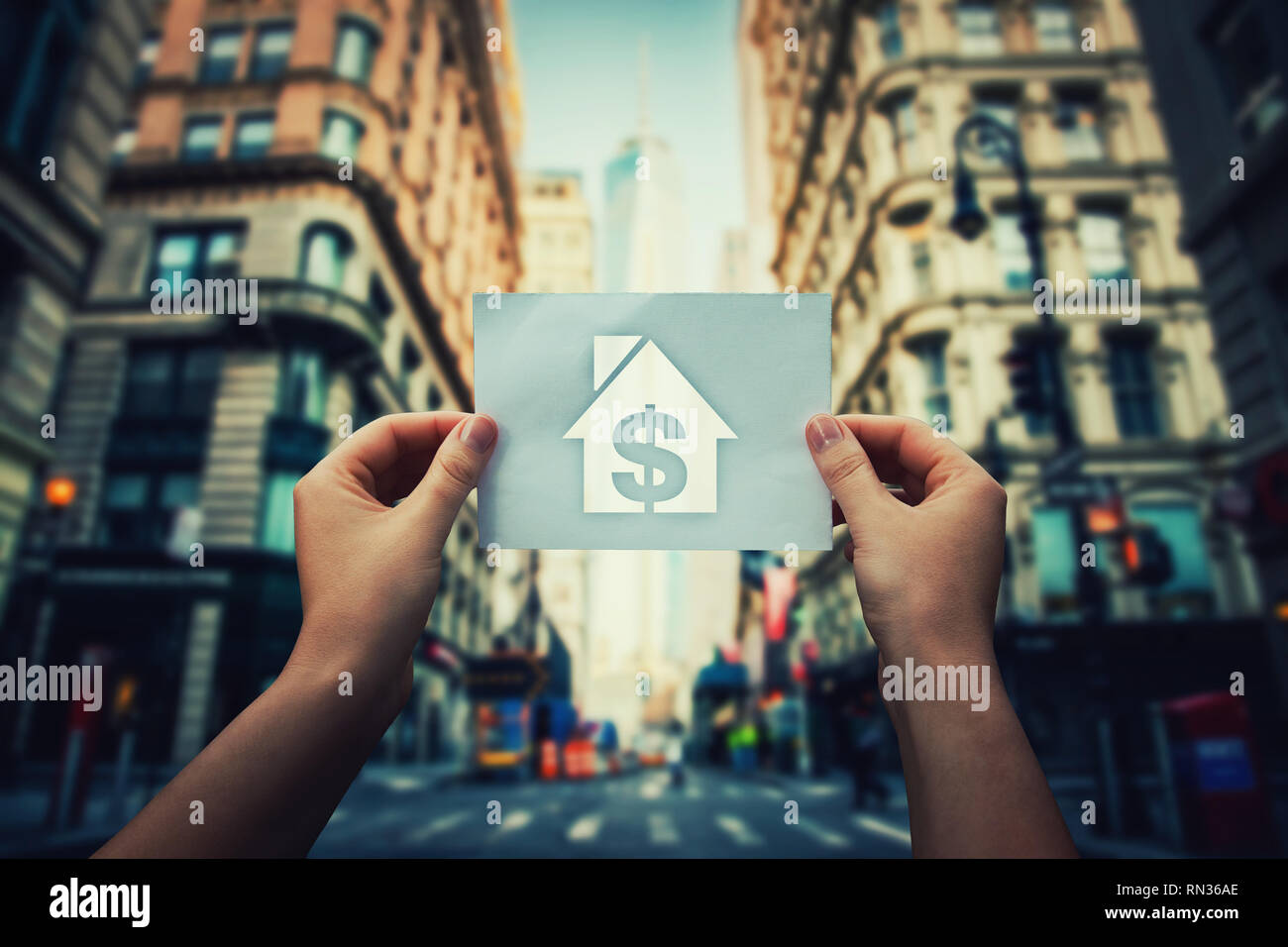 Armut und Obdachlosigkeit globales Thema Konzept als Frau Hände halten ein Blatt Papier mit Haus und Dollar Symbol in der Mitte der Straße von ein Stockfoto