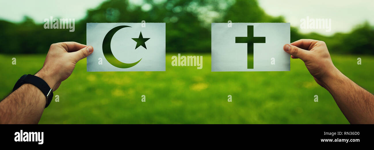Religion Konflikte als globales Thema Konzept. Zwei Hände, die anderen glauben Symbole, den Islam, das Christentum glauben über grüne Feld Natur vs. Beziehungen Stockfoto