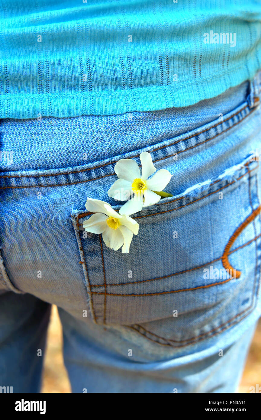 Rückansicht eines Jugendlichen tragen ein Paar verblassten und abgenutzte blaue Jeans. Sie hat zwei Blumen in die hintere Tasche verstaut. Stockfoto